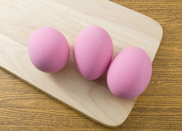 Huevo del siglo rosa en una tabla de cortar de madera
 - Foto, Imagen