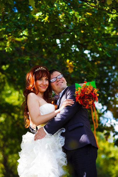 νύφη και ο γαμπρός που στέκεται πάνω σε πράσινο φόντο στο δάσος, κόκκινα μαλλιά - Φωτογραφία, εικόνα