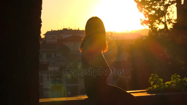 lonely Young woman silhouette sitting on the roof looking the city sunset - Footage, Video