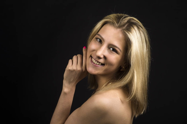 Portrait of a smiling girl on a dark background. - Фото, изображение