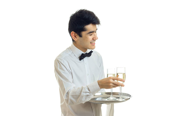 smiling lovely waiter takes a glass of wine with a tray - Photo, Image