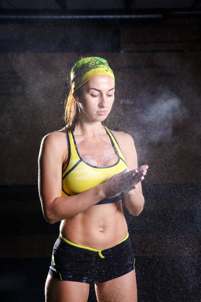 Modelo de fitness femenino aplaudiendo manos con talco en polvo en un gimnasio justo antes de hacer ejercicio
. - Foto, imagen