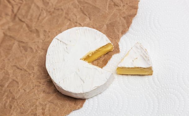 Fresh slice Camembert cheese natural, on Kraft paper - Foto, imagen