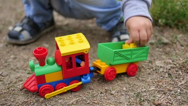 Un niño juega con un tren de juguete en la arena. Juegos al aire libre
 - Metraje, vídeo