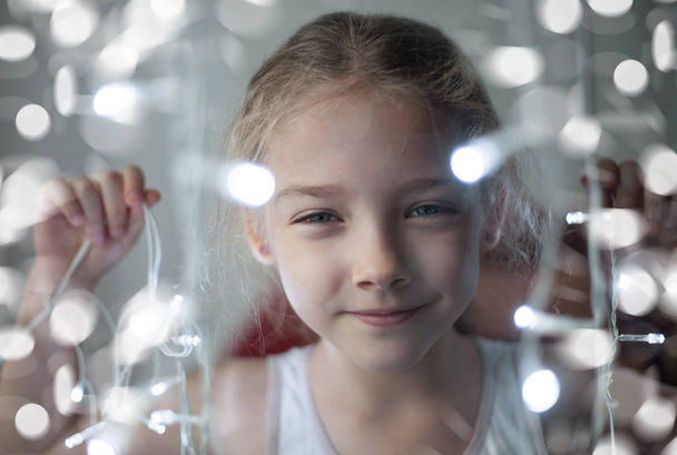 A sugárzó füzér a fények a kezében egy aranyos lány, óvodai portré. - Fotó, kép
