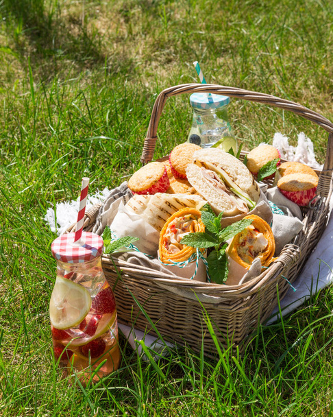 Cesta de picnic con comida en césped verde soleado
 - Foto, Imagen