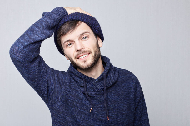Human face expressions and emotions. Portrait of excited young Caucasian bearded hipster man looking happily at camera wearing blue hat and touching his head. - Photo, Image