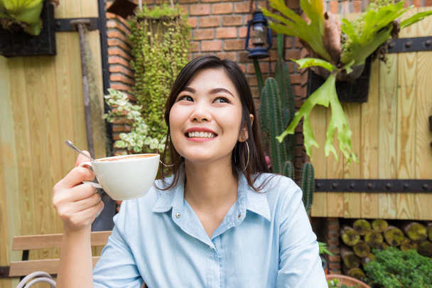 アジアの女性が白ラテ アート コーヒー カップでリラックスします。 - 写真・画像