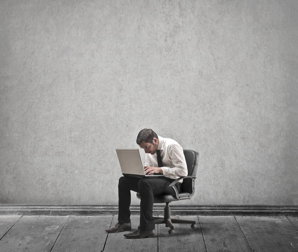Tired businessman with laptop sitting inside - Zdjęcie, obraz