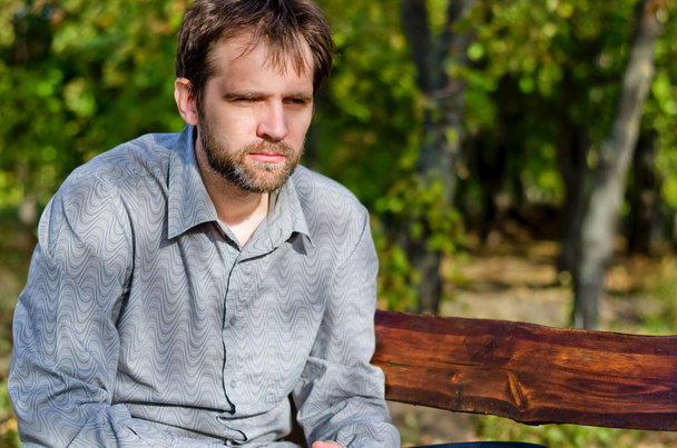 Mann sitzt denkend auf einer Holzbank - Foto, Bild