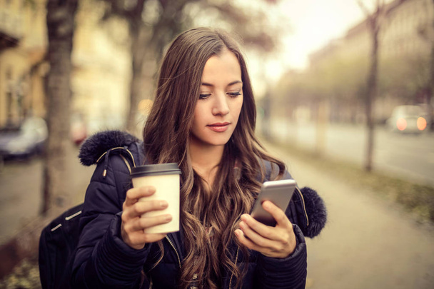 Young brunette woman looking at her phone - Fotó, kép