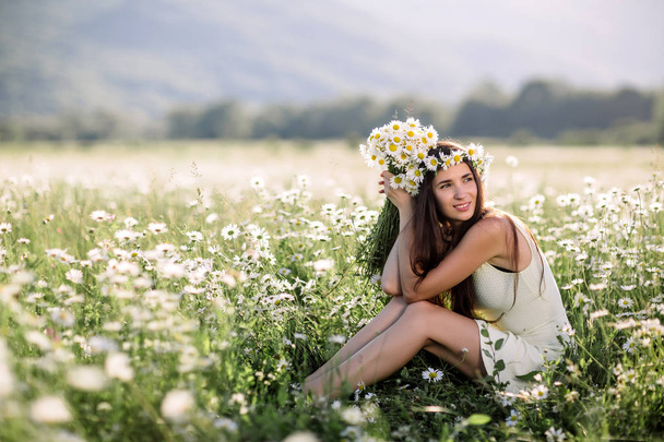 Beautiful woman enjoying daisy field, nice female lying down in meadow of flowers, pretty girl relaxing outdoor, having fun, holding plant, happy young lady and spring green nature, harmony concept - Foto, Imagem
