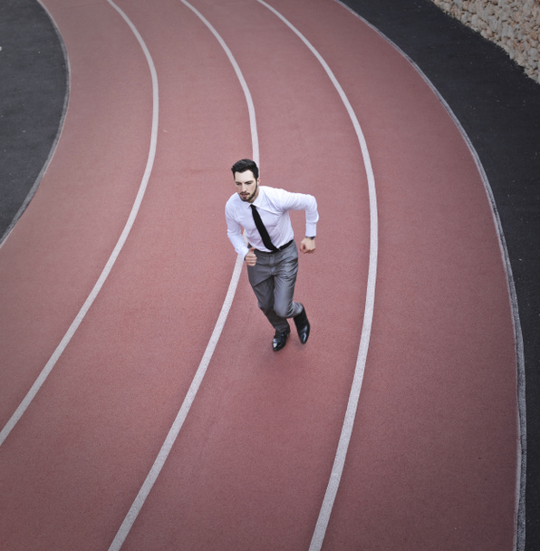Liikemies juoksemassa juoksukentällä ulkona
 - Valokuva, kuva