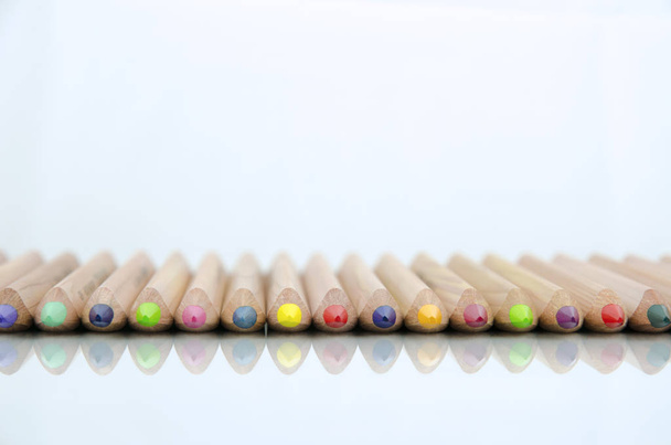 Close-up view of colored pencils lying on glossy white background with reflection isolated on white background - 写真・画像