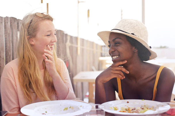 2 молодые женщины едят вне дома
 - Фото, изображение