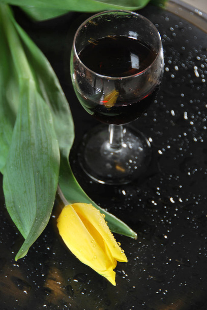 A glass of red wine with a tulip in the rain - Фото, изображение