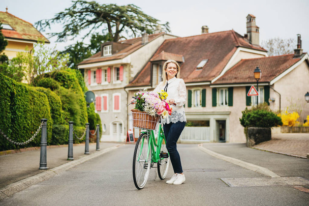 Nane renk Bisiklet büyük renkli buket çiçek sepeti ile yanında duran güzel sarışın kadın - Fotoğraf, Görsel