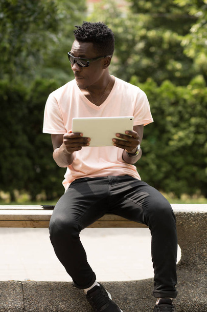 Black man using white tablet PC - Фото, зображення