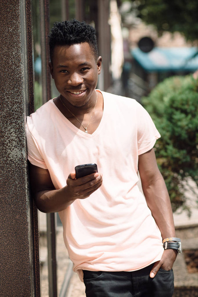 Uomo afroamericano che utilizza il cellulare nella città estiva
 - Foto, immagini