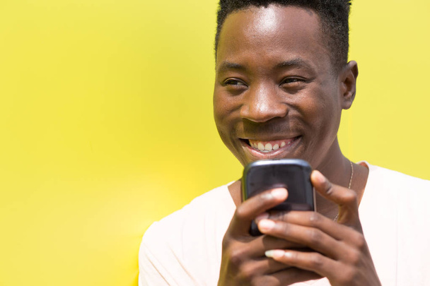 African american man using cellphone on yellow background - Fotografie, Obrázek