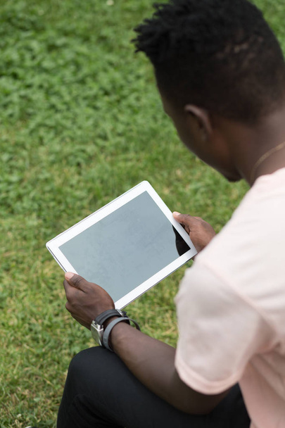 African american male hands holding tablet pc on grass background - Photo, image