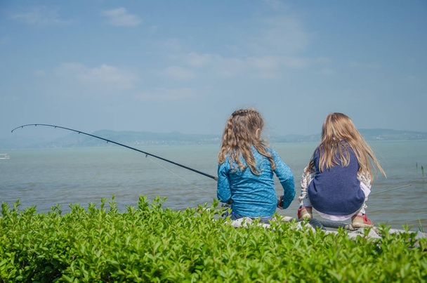 twee meisjes vissen in het meer - Foto, afbeelding