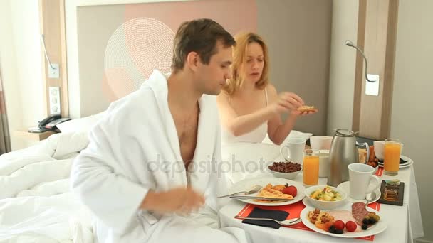 Young couple man and woman having breakfast on bed in apartment - Πλάνα, βίντεο
