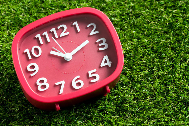 Orologio analogico rosso su sfondo erba verde artificiale
 - Foto, immagini