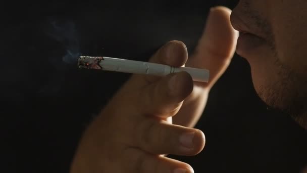 Człowiek palenia papierosów na czarnym tle, klip Hd. - Materiał filmowy, wideo