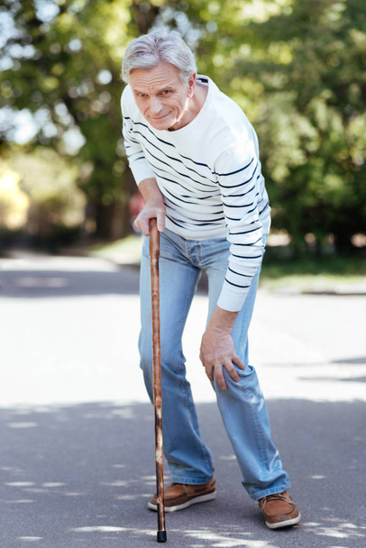 Confused pensioner feeling ache in knee outdoors - Фото, изображение