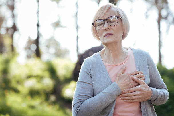 Overwhelmed pensioner having heart attack outdoors - Photo, image