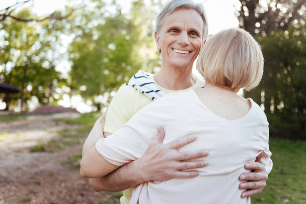 Happy pensioner hugging his wife in the park - Фото, изображение