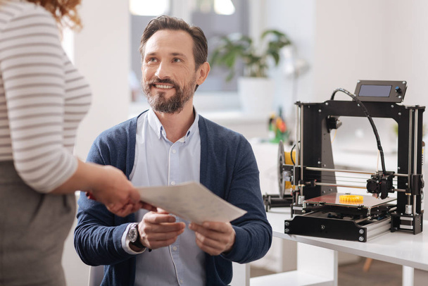 Joyful handsome man sitting in front of the 3d printer - Photo, Image