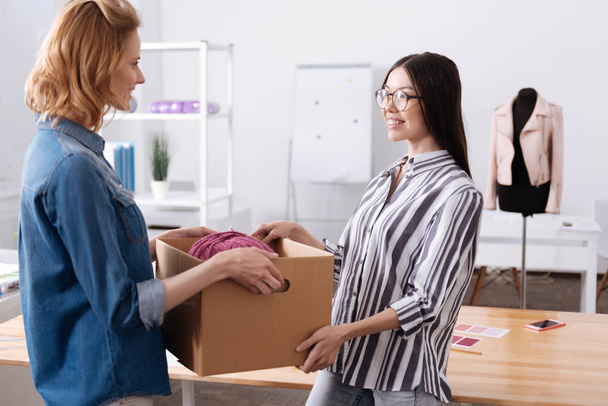 Pleasant woman helping her colleague to carry a box - Photo, Image