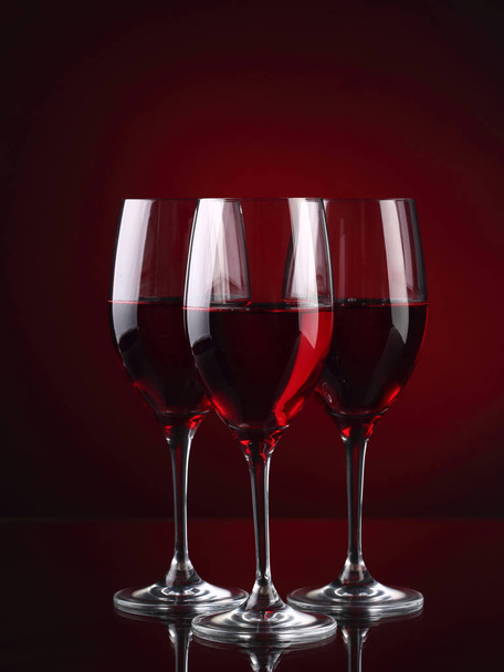 Three wineglasses with some wine on red - Foto, Imagem