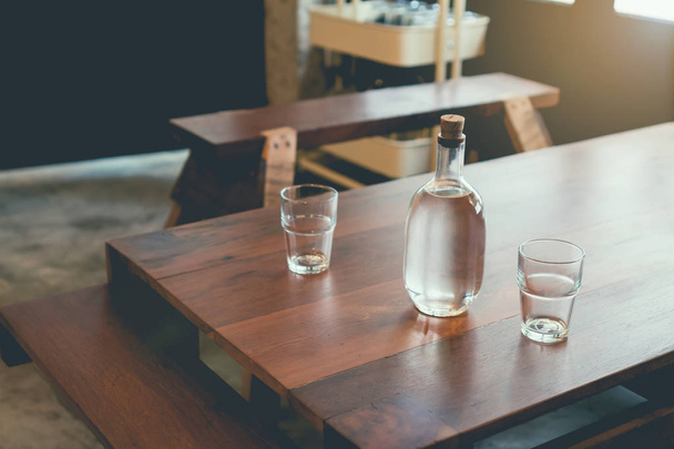 Foco suave de garrafas de água e vidro são colocados em uma mesa de madeira em um café, esperando que os clientes peçam comida. tom vintage
 - Foto, Imagem