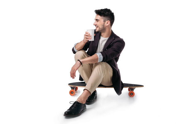 man drinking beverage while sitting on skateboard - Foto, Imagen