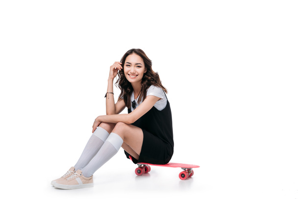 sonriente asiático chica sentado en skateboard
 - Foto, Imagen