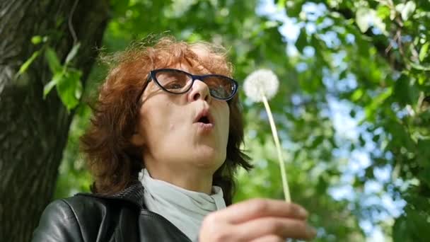 Happy woman blowing dandelion seeds in the Park , slow motion - Footage, Video