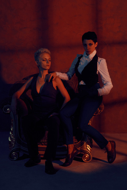 two lesbians with serious look in old armchair - Foto, imagen