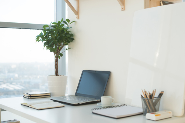 Imagen vista lateral del lugar de trabajo del estudio con cuaderno en blanco, computadora portátil. Diseñador mesa de trabajo cómoda, oficina en casa
. - Foto, Imagen