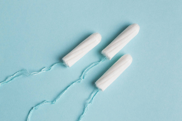 Menstrual tampon on a blue background. Menstruation time. Hygiene and protection - Photo, Image