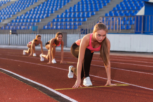 Fiatal nő sportoló a kiindulási helyzet indulásra készen a verseny. - Fotó, kép