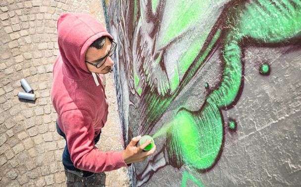 Vista superior de artista callejero pintando graffiti de colores en la pared genérica. Filtro neutro de tarde soleado
. - Foto, imagen