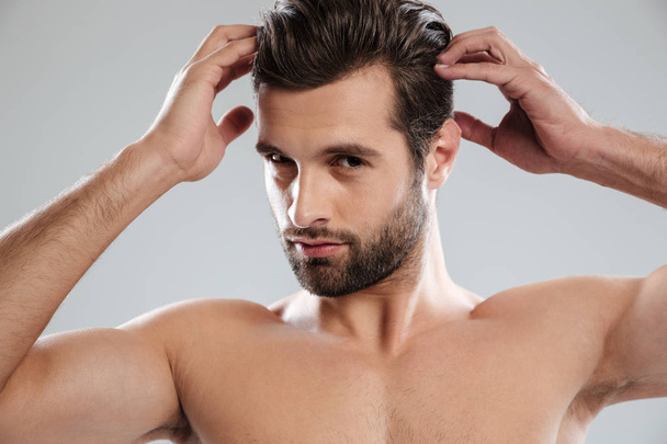 Charming naked bearded man posing and touching his hair - Foto, afbeelding