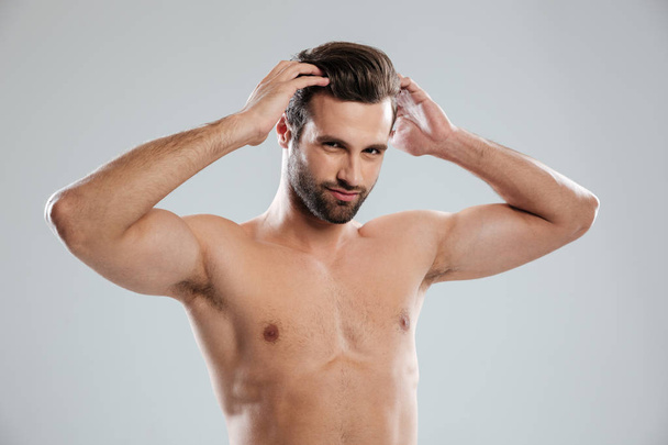 Charming naked bearded man posing and touching his hair - Фото, изображение