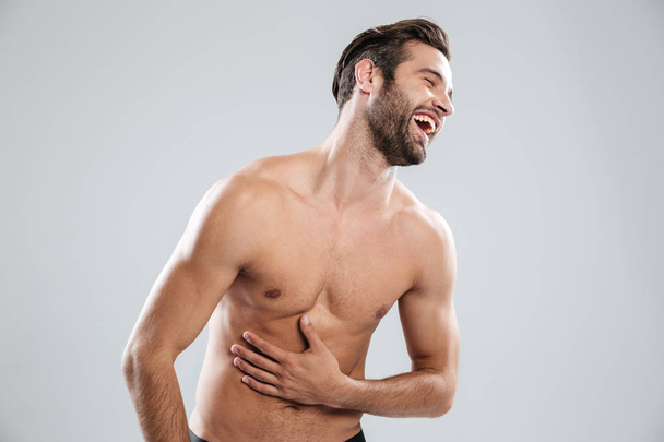 Portrait of a bearded shirtless man doubling up with laughter - Foto, Bild