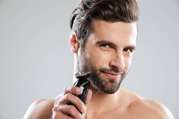Handsome young man holding electric razor - Φωτογραφία, εικόνα