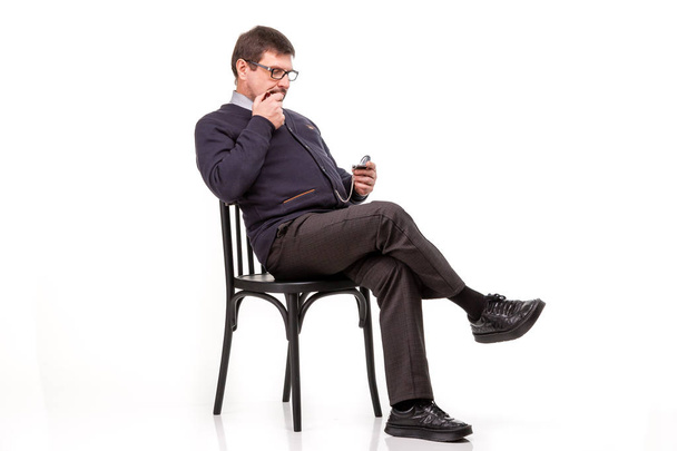 Een knappe man in een pak en glazen, zit, met een pijp voor smok - Foto, afbeelding