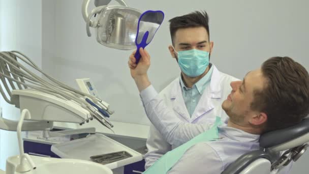 O paciente olha para os dentes no espelho no consultório do dentista.
 - Filmagem, Vídeo